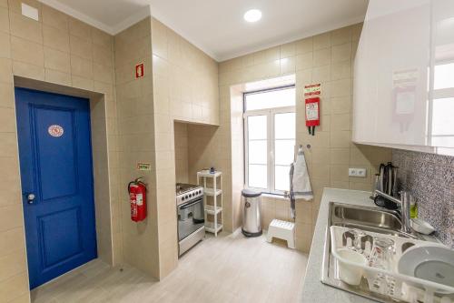 a small kitchen with a blue door and a sink at Help Yourself Hostels - Parede in Parede