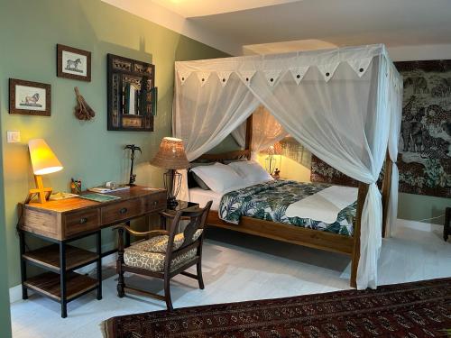 a bedroom with a bed with a desk and a canopy bed at Habitation Tara in Capesterre-Belle-Eau