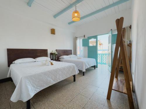 two beds in a room with white sheets at Casa Ramona in Flores