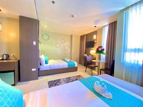 a hotel room with two beds and a desk at Hotel Estrella in Tacloban