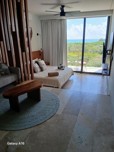 a bedroom with a bed and a couch and a large window at Beach Studio Playa del Carmen MX in Playa del Carmen