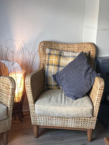 a wicker chair with a pillow in a room at Moat View Donaghadee in Donaghadee