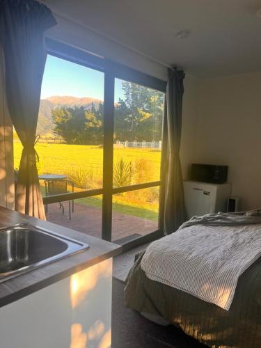 a bedroom with a bed and a kitchen with a window at Adorable studio cottage with mountain views in Staveley