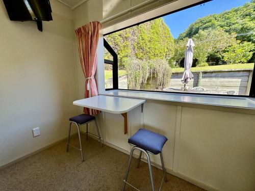ein Raum mit einem Tisch und zwei Hockern vor einem Fenster in der Unterkunft Ridgehaven Accommodation in Opotiki