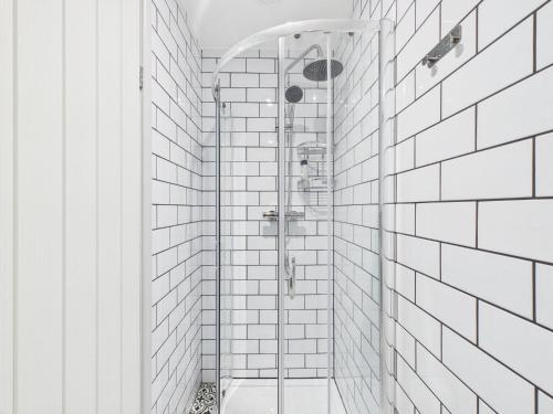 a shower in a white bathroom with white tiles at The Costwold Haven in Shurdington