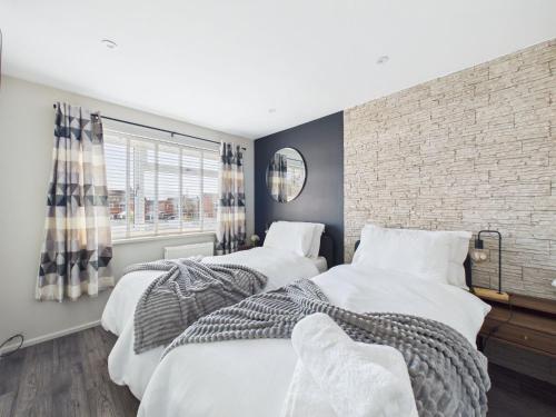 two beds in a bedroom with a brick wall at The Costwold Haven in Shurdington