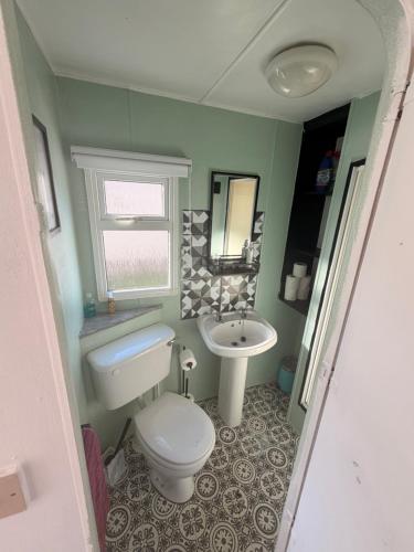 a small bathroom with a toilet and a sink at Hoopers Hideaway Caravan Rental SetonSands 2 in Port Seton