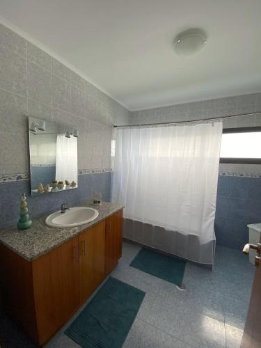 a bathroom with a sink and a white shower curtain at Refugio do Falcão in Ponta Garça