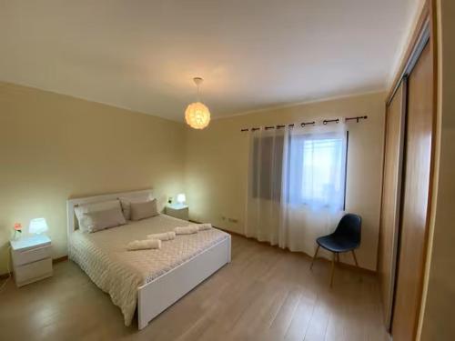 a bedroom with a bed and a chair and a window at Refugio do Falcão in Ponta Garça