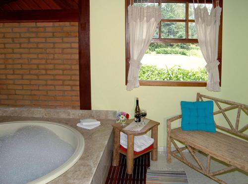 a bathroom with a tub and a chair and a window at Pousada do Encanto in Visconde De Maua