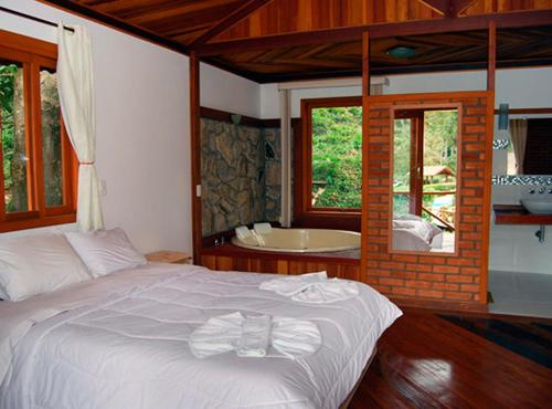 a bedroom with a bed and a tub in a room at Pousada do Encanto in Visconde De Maua