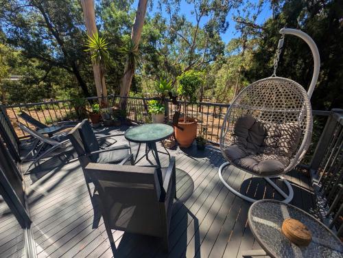 a deck with chairs and a swing and a table at A Heavenly Escape in Halls Gap