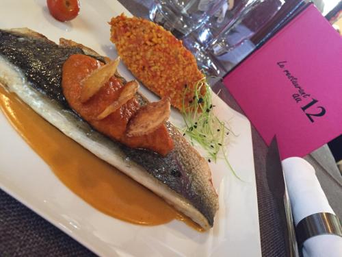 a plate of food with a piece of fish and onion rings at Hôtel L'Auberge Alsacienne in Eguisheim