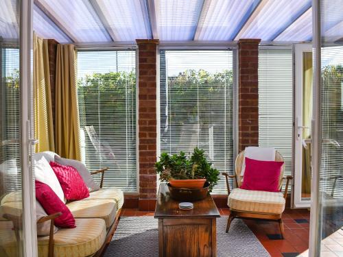 a living room with a couch and two chairs and windows at Why Not in Canterbury