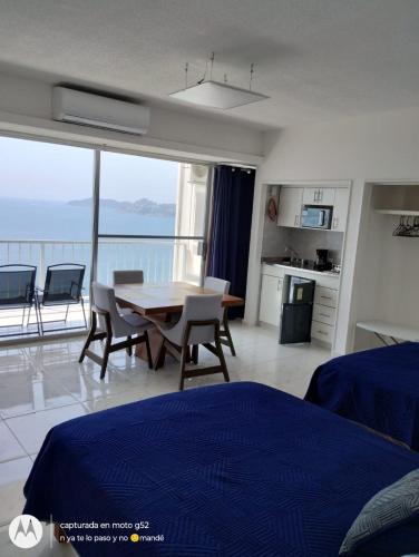 a bedroom with a table and chairs and a balcony at Suite Frontal a Pie de Playa con Terraza Panorámica in Acapulco