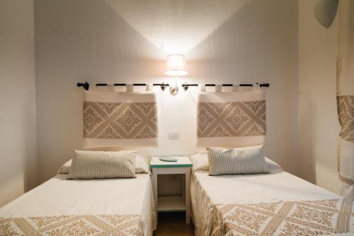 two beds in a room with a table between them at Le Ville Le Saline in Palau