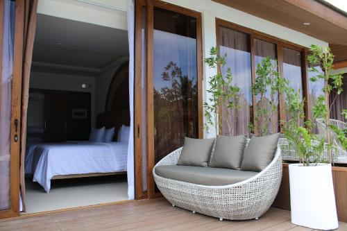 a wicker chair sitting on a porch with a bedroom at Dahican Beach Resort and Spa in Sampong