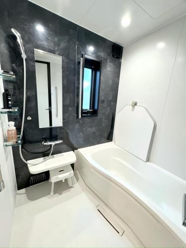 a bathroom with a white tub and a sink at Akikawa Koshi 2 プレミアム鉄骨 一棟貸切ヴィラ in Yuge
