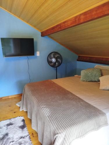 a bedroom with two beds and a flat screen tv at Chalé Studio Haven, microcasa com Mezanino e banheira in Lumiar