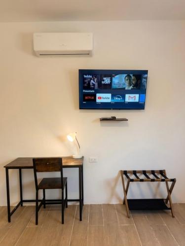 a desk with a chair and a tv on a wall at Hospedaje Suites Aeropuerto Villahermosa in Villahermosa