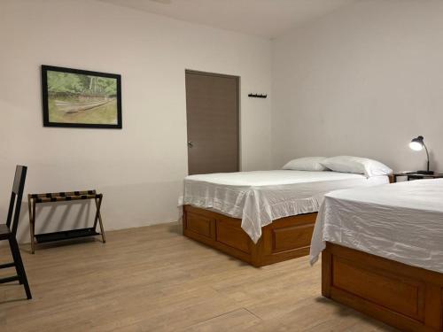 a bedroom with two beds and a chair in it at Hospedaje Suites Aeropuerto Villahermosa in Villahermosa