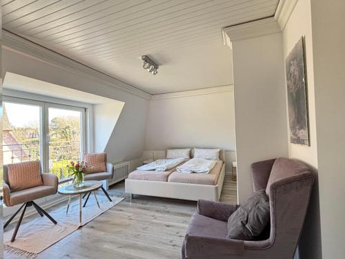 a living room with a bed and two chairs at Ferienwohnung-Weidenstieg-OG in Wenningstedt