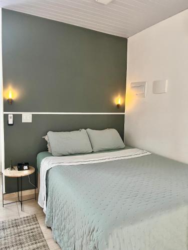 a bedroom with a bed with a green wall at Loft 967 in Itajaí