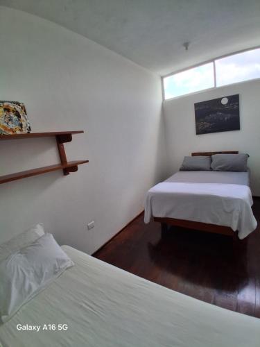 a white bedroom with two beds and a window at Pescadito in Puerto Ayora