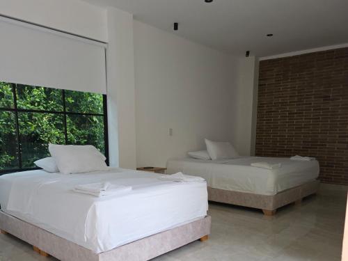 a bedroom with two beds and a large window at Casa Mezcal in Villeta