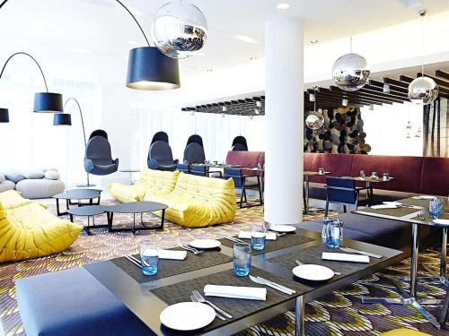 a restaurant with yellow furniture and tables and chairs at Novotel London Brentford in Brentford