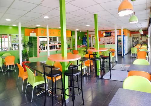Fasthotel Poitiers Futuroscope في جوانيه - كلان: مطعم به طاولات وكراسي خضراء و برتقالية