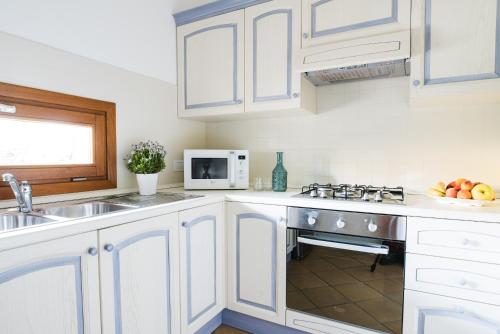 a kitchen with white cabinets and a sink and a microwave at Le Ville Le Saline in Palau