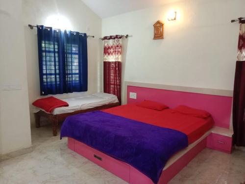 a bedroom with a red and purple bed and a chair at HALASE HOMESTAY mudigere in Mudigere