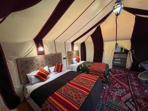 a bedroom with two beds in a tent at Fantastic Luxury Dunes Camp in Merzouga