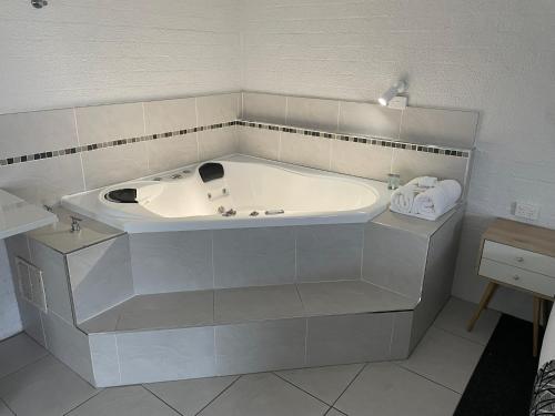 a white tub in a bathroom with a sink at Coastal Bay Motel in Coffs Harbour