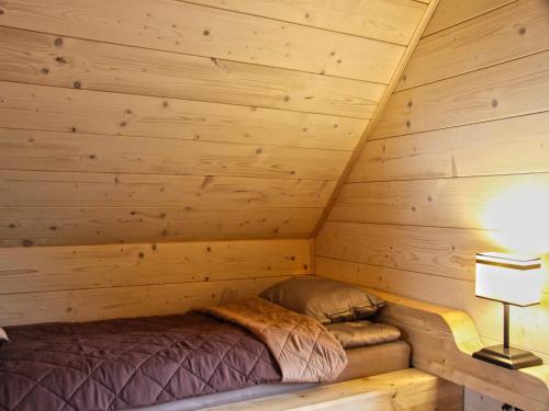 a bed in a log cabin with a lamp at Holiday homes with fireplaces, playground in Lubrza