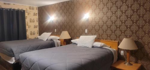a hotel room with two beds and two lamps at Neepawa Motel in Neepawa