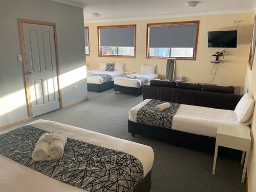 a hotel room with two beds and a couch at Coastal Bay Motel in Coffs Harbour