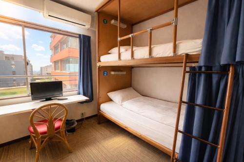 a room with bunk beds and a desk and a computer at Sakura Hotel Jimbocho in Tokyo