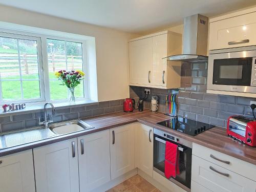 a kitchen with white cabinets and a sink and a microwave at Colby Hall Cottage in Colby