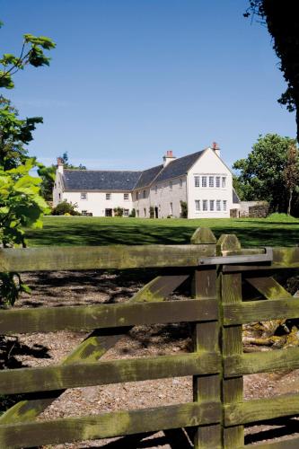a fence in front of a white house at The Glenmorangie House in Tain