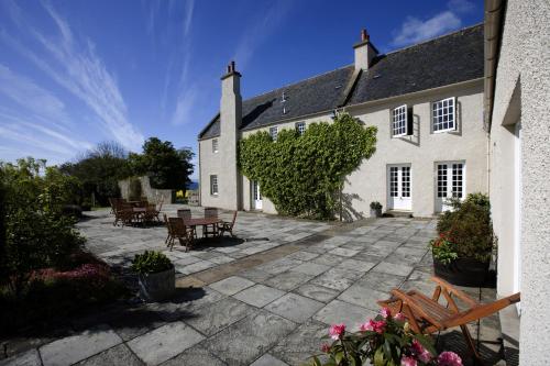 a house with a patio and tables and chairs at The Glenmorangie House in Tain