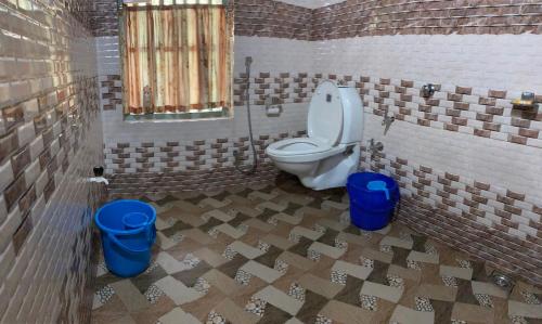 a bathroom with a toilet and two blue trash cans at Kakkakuni heritage in Kozhikode