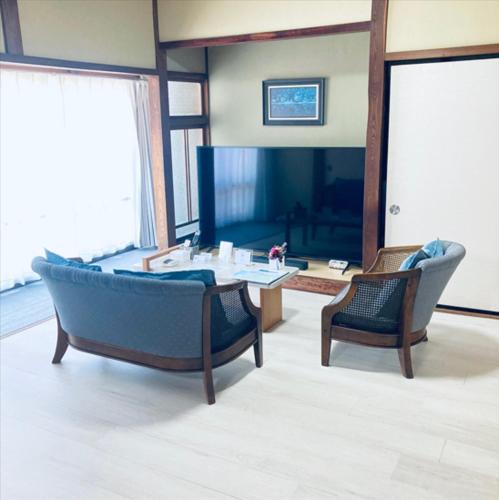 a living room with a couch and a table and chairs at 福のや in Unnan