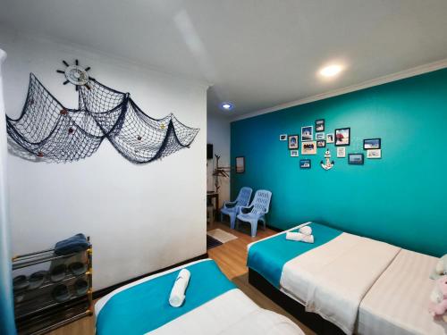 a bedroom with two beds and a blue wall at 爱上海蓝蓝屋民宿 Blue Ocean Station in Penampang