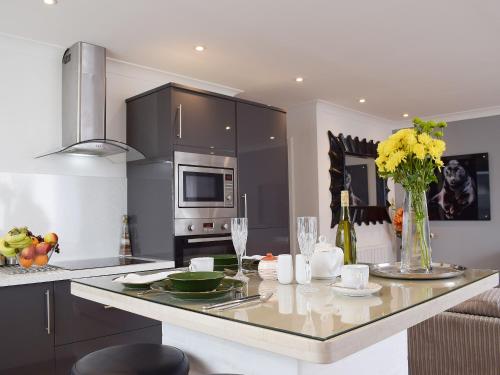 a kitchen with a counter with a table with flowers at Bramble Cottage in Leven