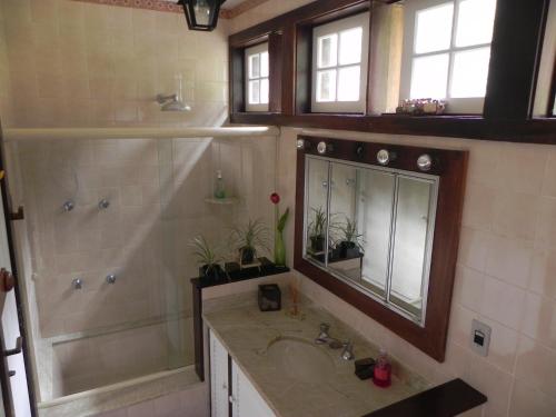 a bathroom with a sink and a shower and a mirror at Casa do Fachoalto in Petrópolis