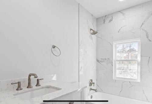 a white bathroom with a tub and a window at Hamptons Tiana Bay Oasis in Hampton Bays