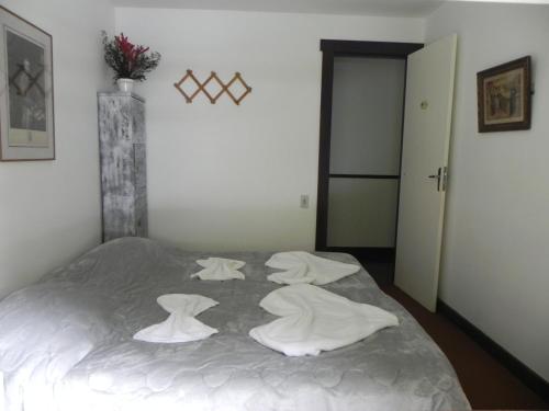 a bedroom with a bed with white sheets on it at Casa do Fachoalto in Petrópolis