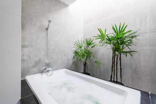 a bath tub with two potted plants in a bathroom at Movenpick Residences 3-Bedroom Pool Villa Beach Access, Na Jomtien Pattaya in Na Jomtien